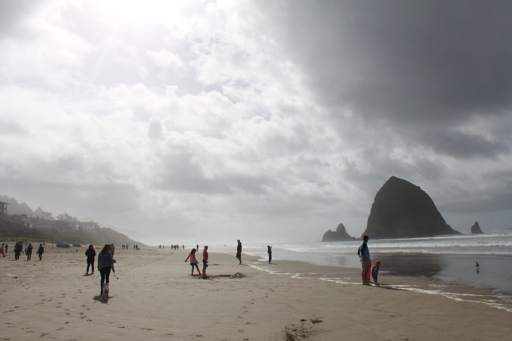people on cannon beach in oregon with haystack rock in the distance