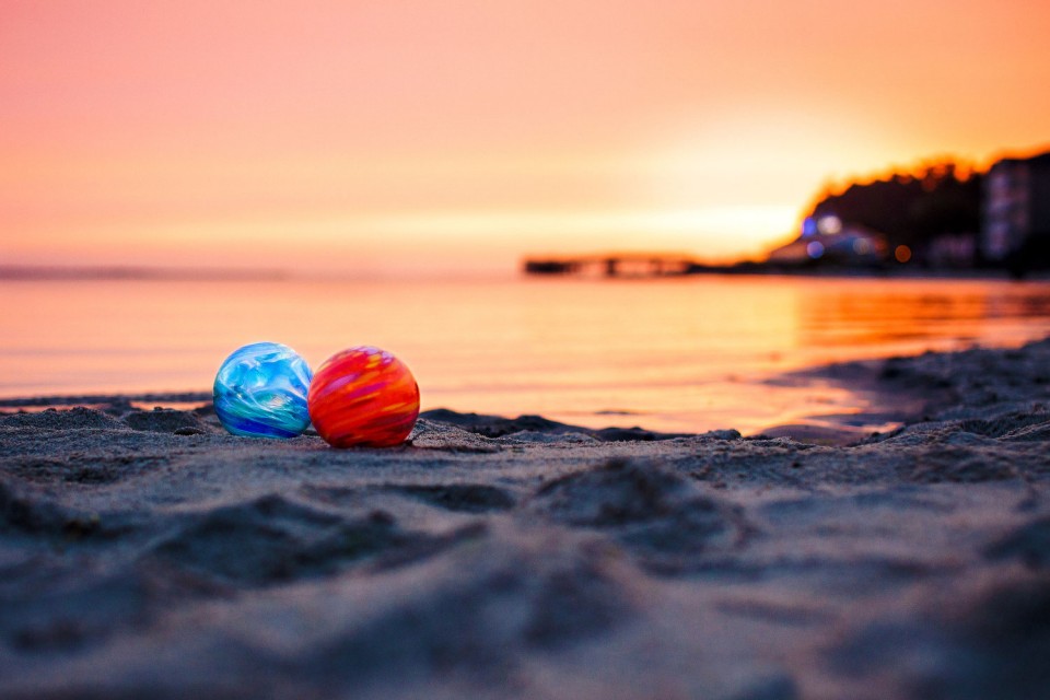 Glass Floats on the beach at sunset. There's a red float and a blue float.