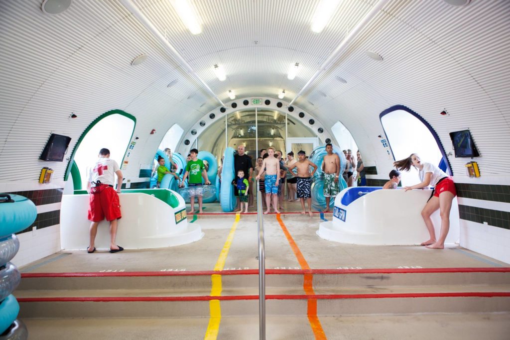 People slide out of the massive plane on the roof and down into the pools below.