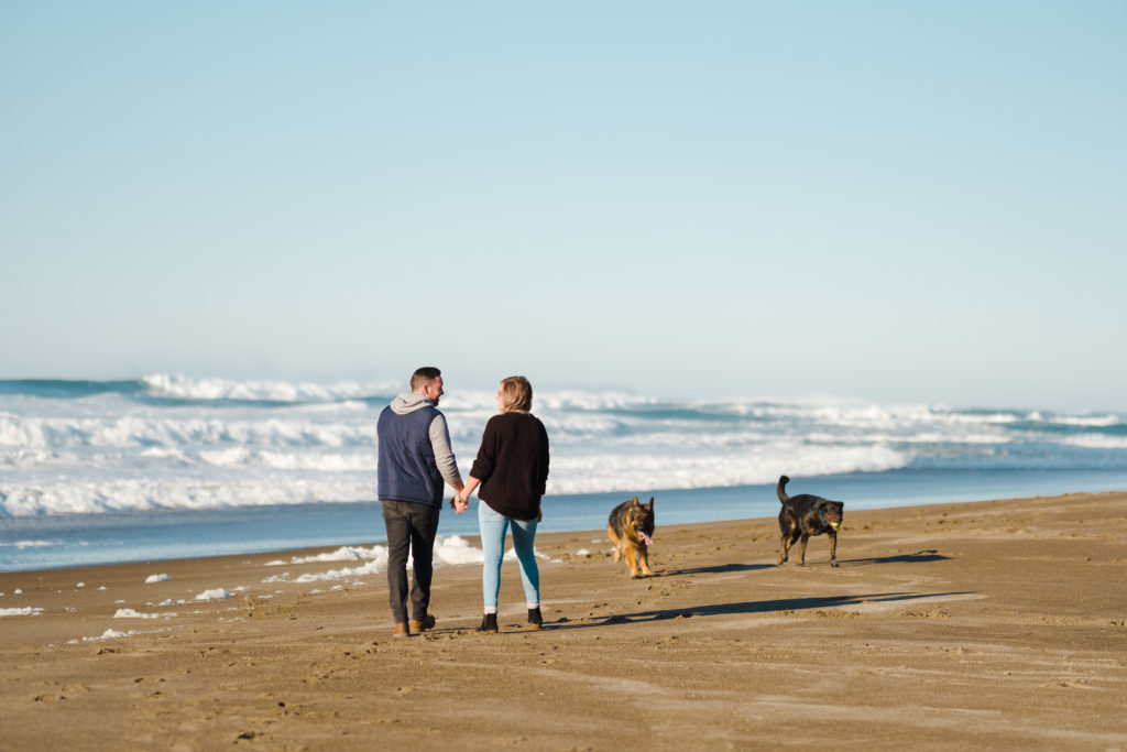 A couple and their dogs walking along the Oregon Coast
