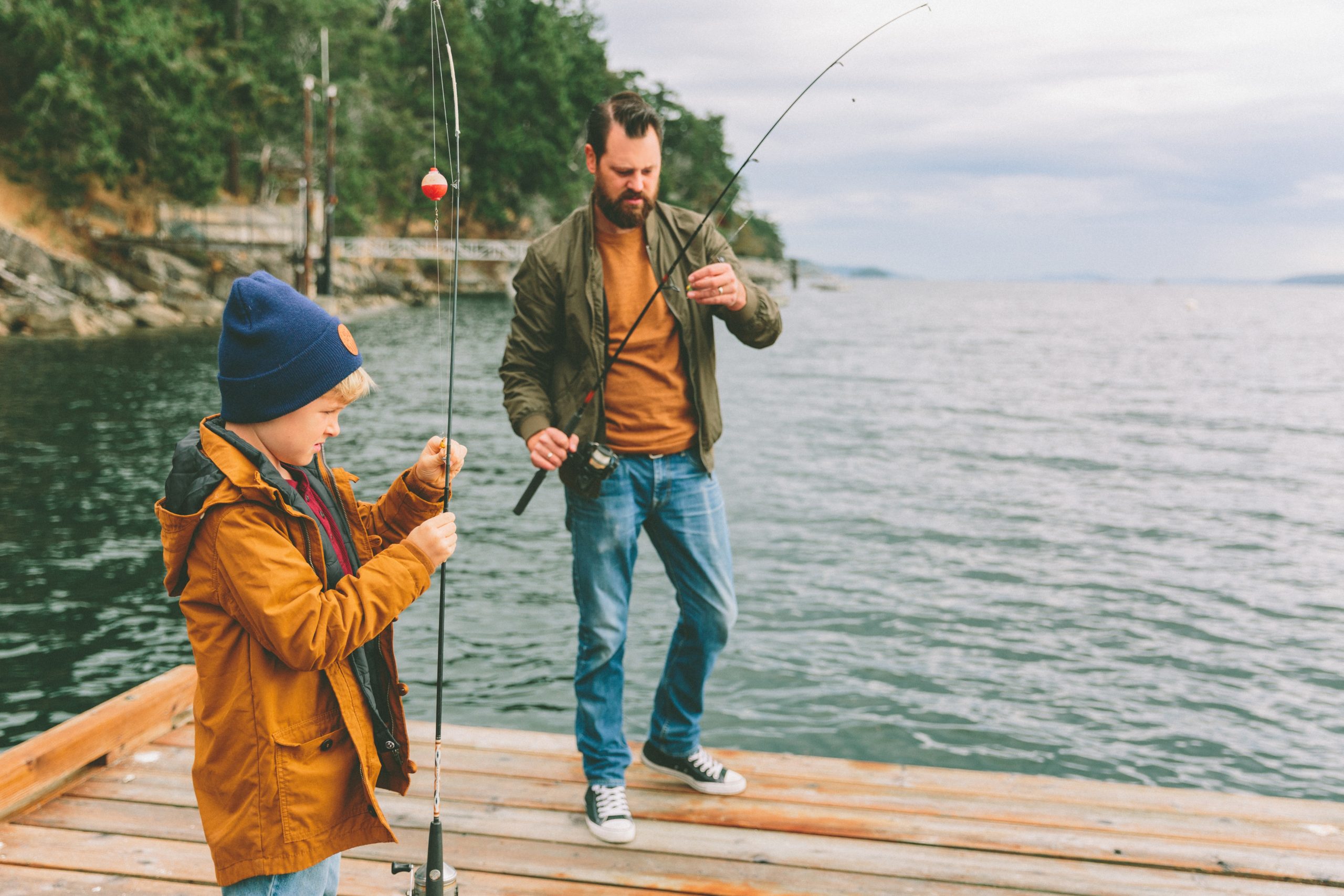 A father and son fishing off a dock at a lake