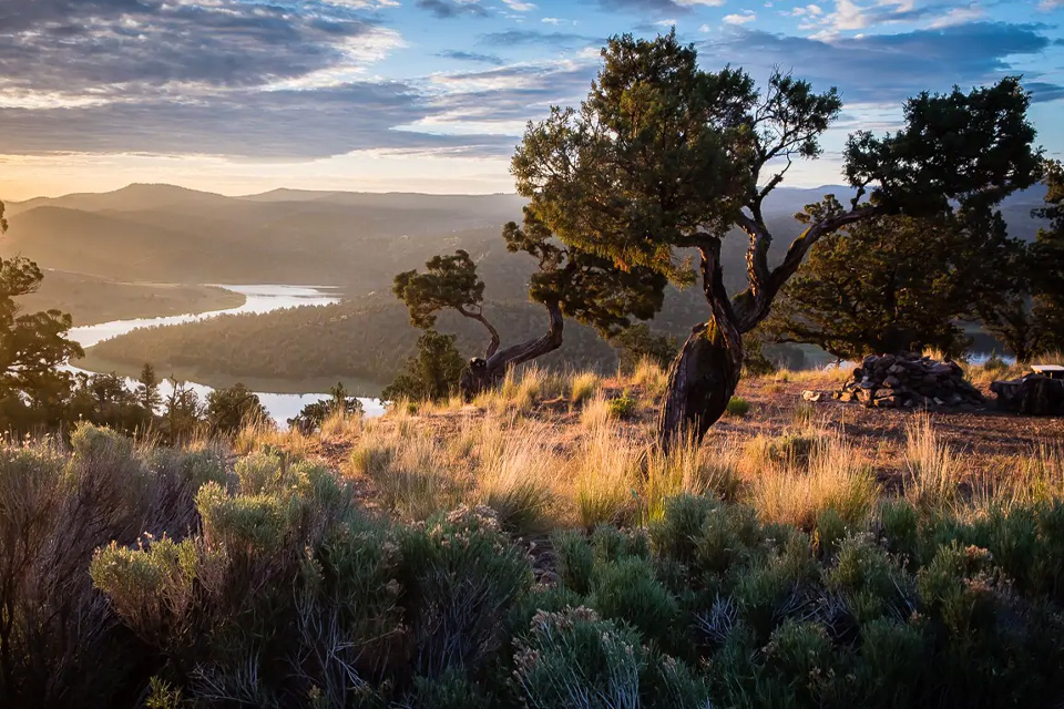 A view of a river going through the desert at sunset