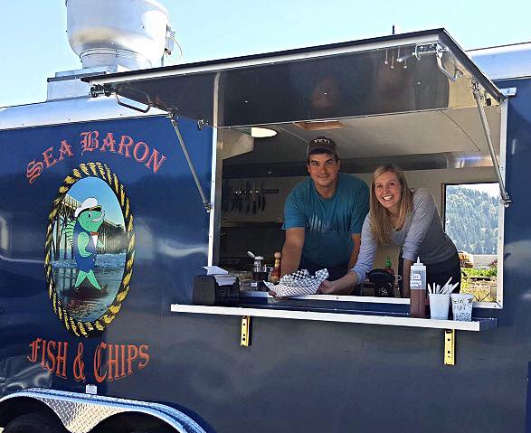 Two people working inside the Sea Baron food truck.