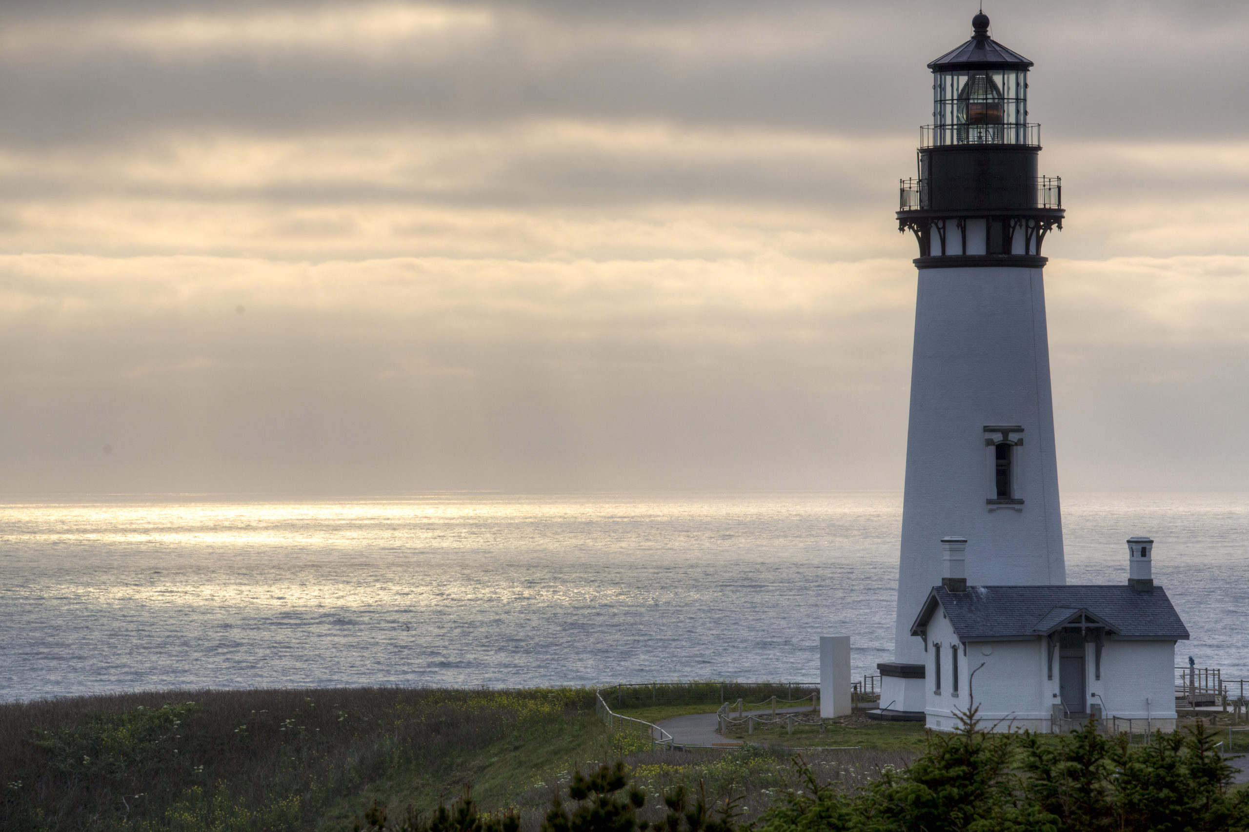 A white lighthouse at sunset overlooking the Pacific Ocean in Oregon.