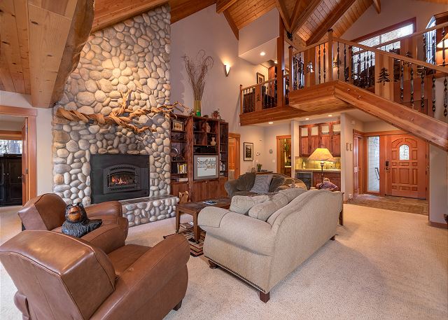 The inside of a gorgeous cabin with a rock fireplace in Sunriver Oregon.