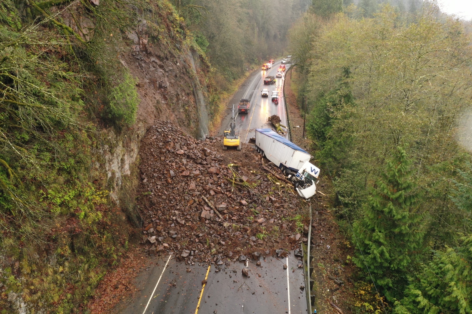 A landslide on the road on US 30 being removed by ODOT crews with the twisted remains of a semi in the debris field.