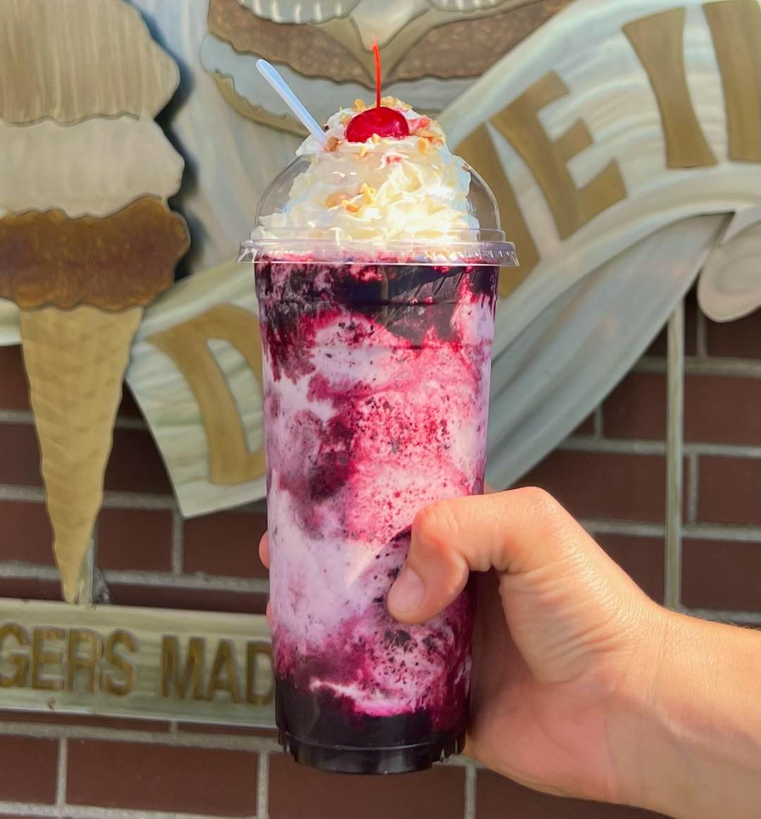A tall colorful purple milkshake with whip cream from Big Jim's Drive In.