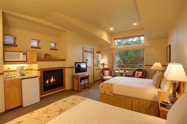 A room with soft cream tones, two beds, and a fireplace at the Inn At Cannon Beach in Cannon Beach, Oregon.