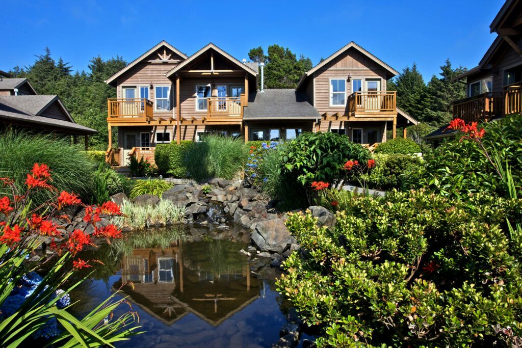 The outside of Inn At Cannon Beach with a small pond and pretty flowers.