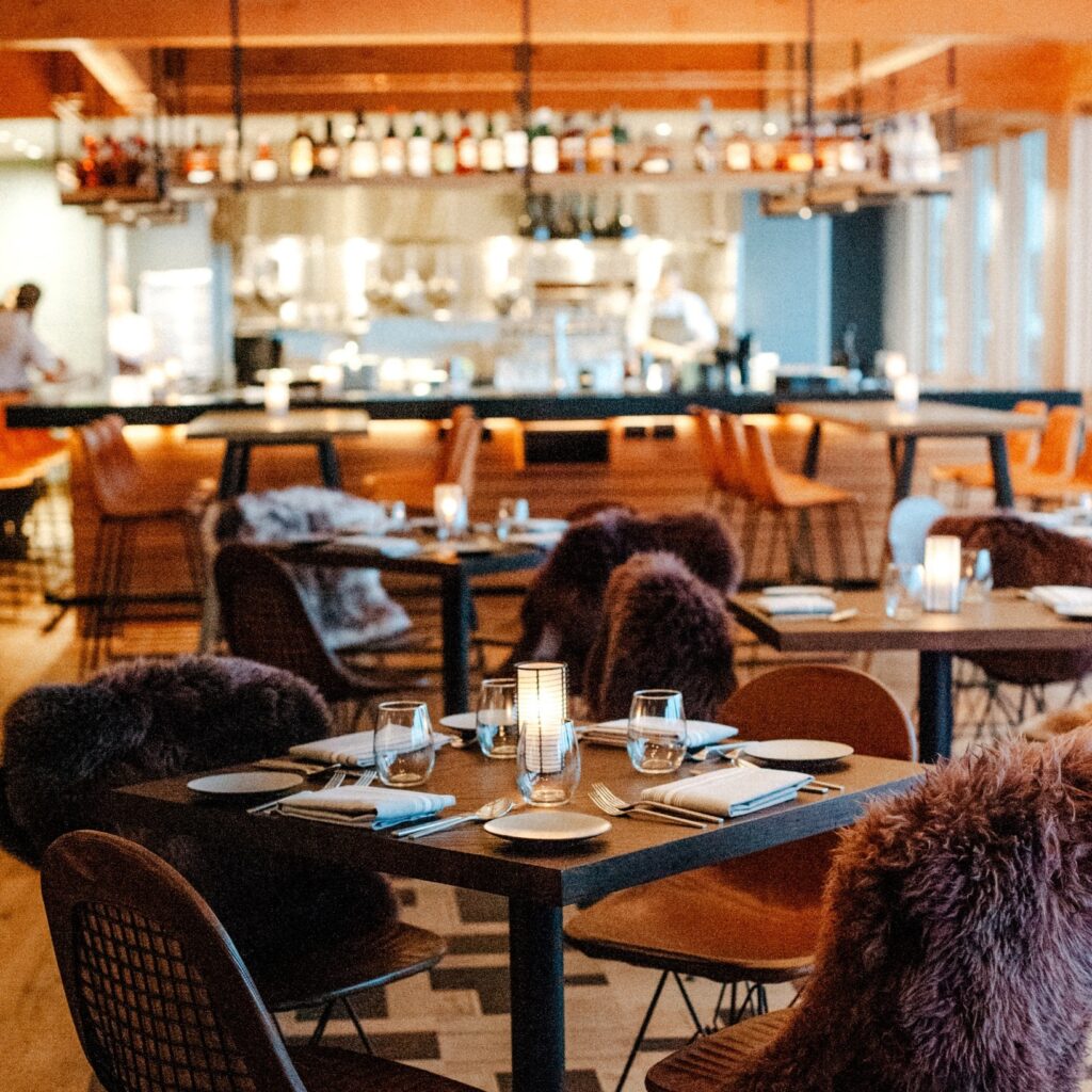 Tables and chairs at the Meridian Restaurant Some chairs have a fluffy black pillow on them.