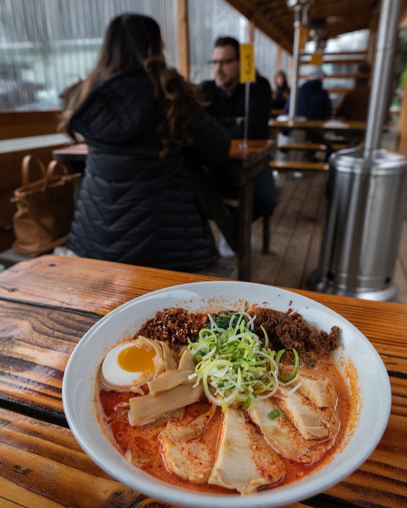 People eat at tables at Kinboshi Ramen in Portland, Oregon. A bowl of delicious looking ramen sits on the table.