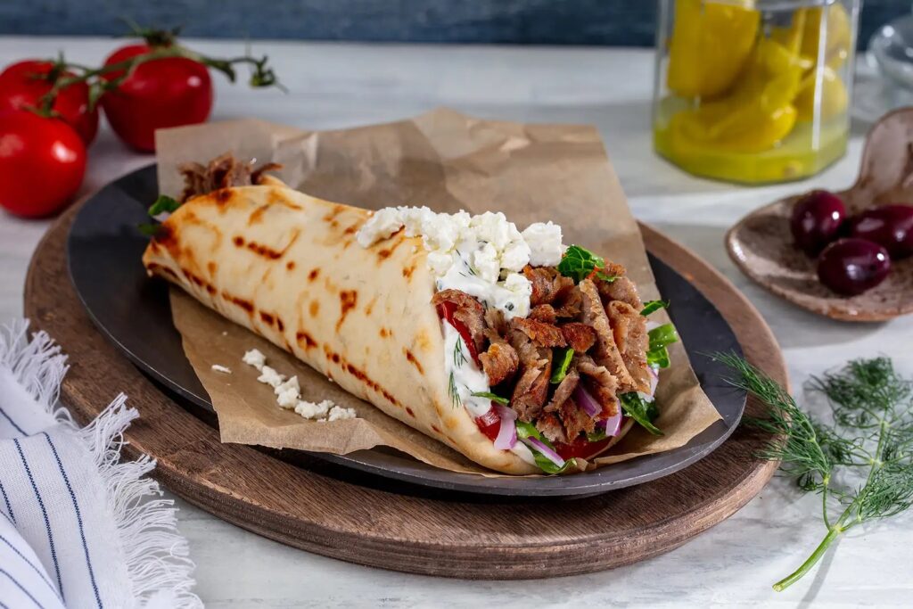 A delicious looking Gyro on a black plate.