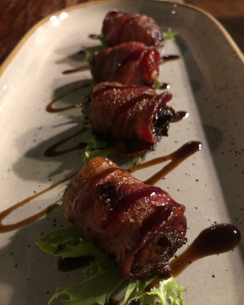 Four bacon wrapped dates lined up on a plate and drizzled with sauce, 3 legged crane, restaurant, best oregon towns, spring road trip, best towns to visit, 2024