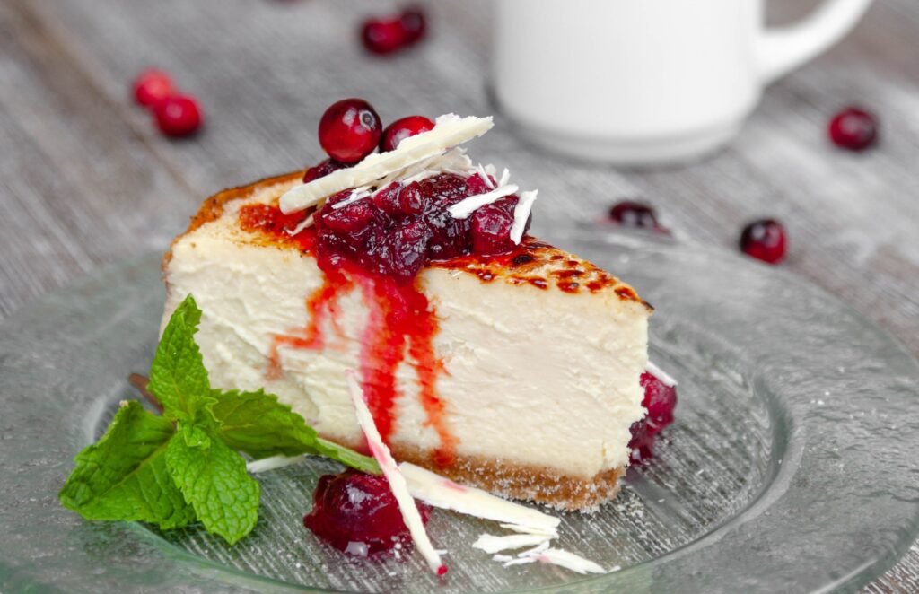 A slice of delicious looking cheesecake with berries and red sauce drizzling down the side from Anthony's.