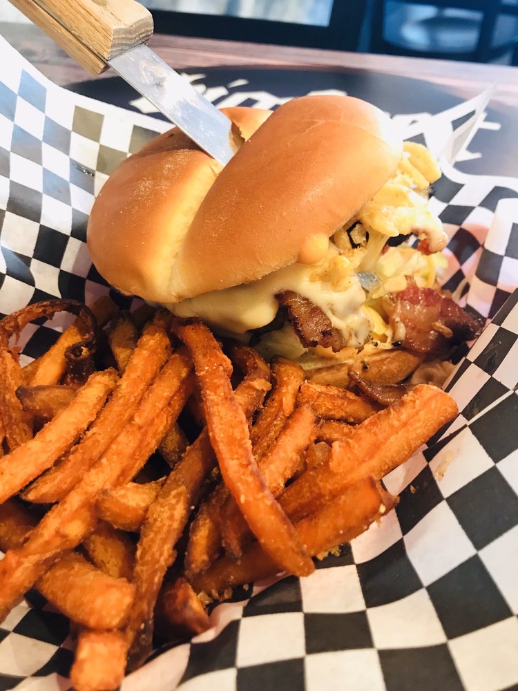 A delicious looking burger with the toppings spilling out the side, and fries on the side.