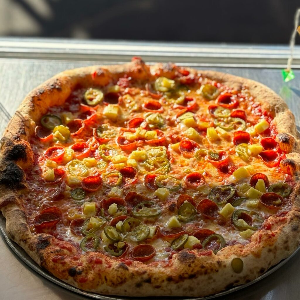 An absolutely delicious and unique looking pizza at Paladin Pie.  Golden window light is shining down on it.  It's got pepperoni and peppers.  This thing looks so good!
portland oregon, best restaurants, 2024, where to eat, best brunch, food and drink, bars, pizza, sushi, thai food, PDX, foodie heaven