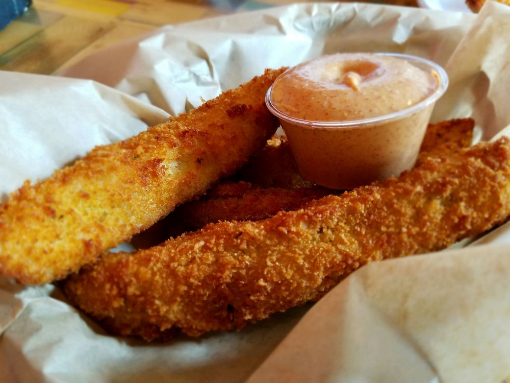 A basket of fried pickles with dipping sauce.